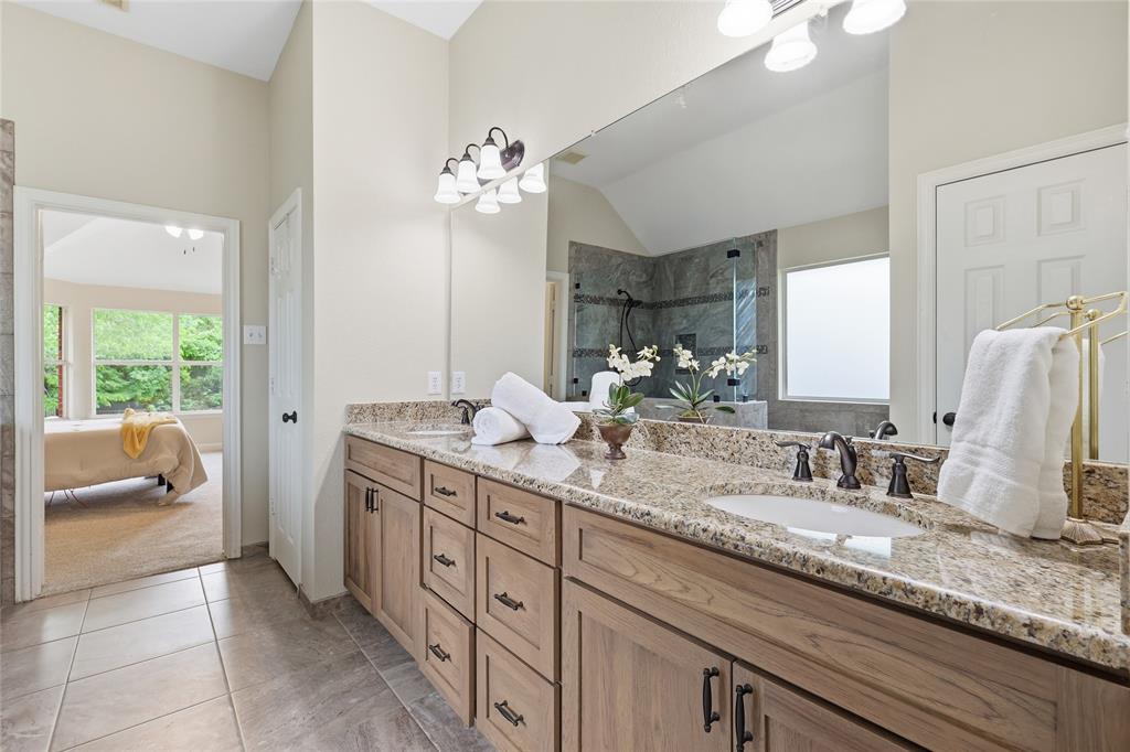 2402 Ravinia Drive Corinth, TX 76208 - Photo 27 of 40 This bathroom features a double vanity with granite countertops, wood cabinetry, and dual sinks