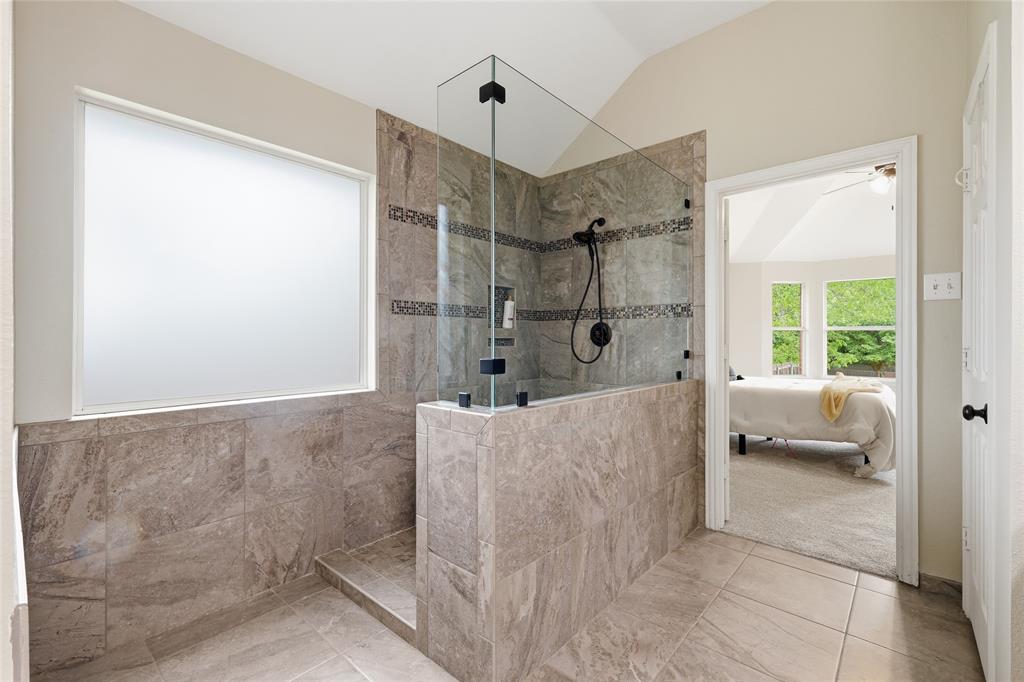 2402 Ravinia Drive Corinth, TX 76208 - Photo 28 of 40 The ensuite bathroom features a spacious walk in shower with glass enclosure, tiled walls, and a frosted window