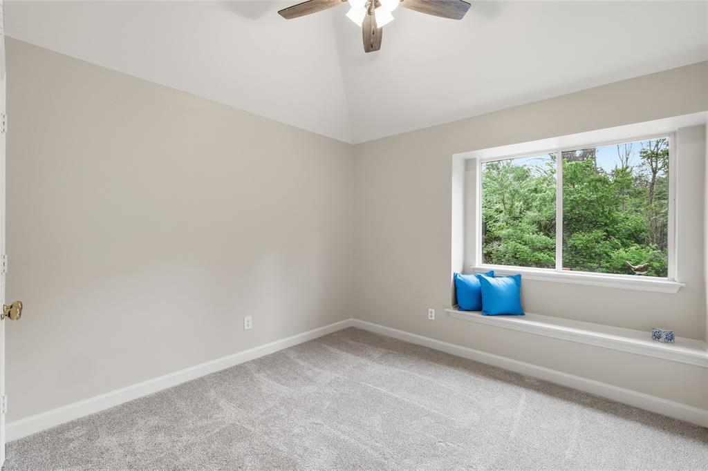2402 Ravinia Drive Corinth, TX 76208 - Photo 32 of 40 The room features a vaulted ceiling with a ceiling fan, a window seat beneath a large window, and light grey carpet