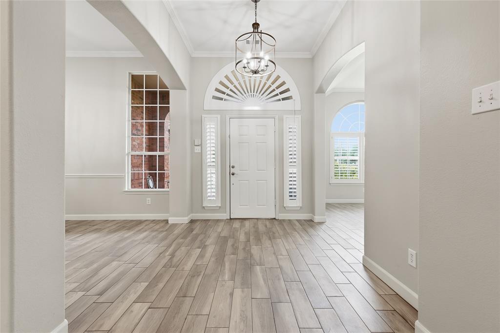 2402 Ravinia Drive Corinth, TX 76208 - Photo 7 of 40 The entryway features wood-look tile flooring, a decorative arched window above the front door, and a chandelier