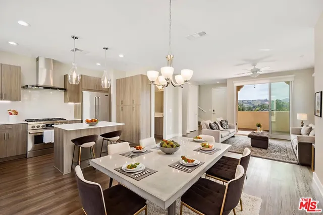 a view of a dining room and livingroom with furniture wooden floor a rug a fireplace and a chandelier