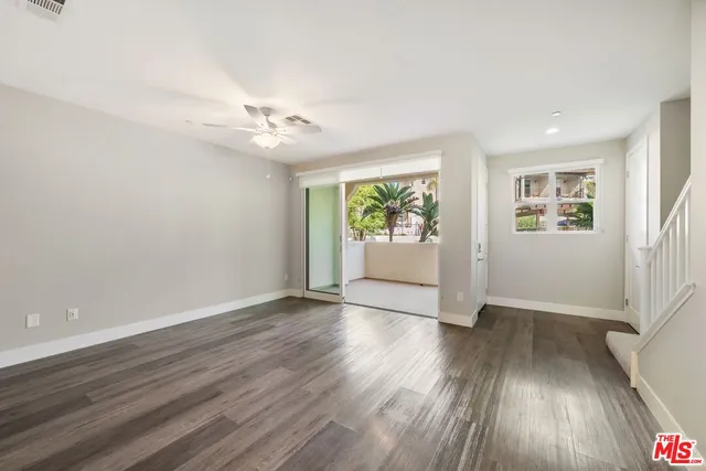 an empty room with wooden floor chandelier fan and windows