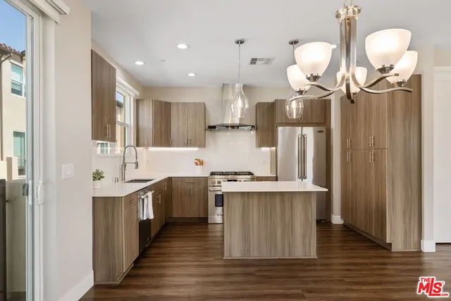 a kitchen with stainless steel appliances granite countertop a sink a stove and a wooden floors