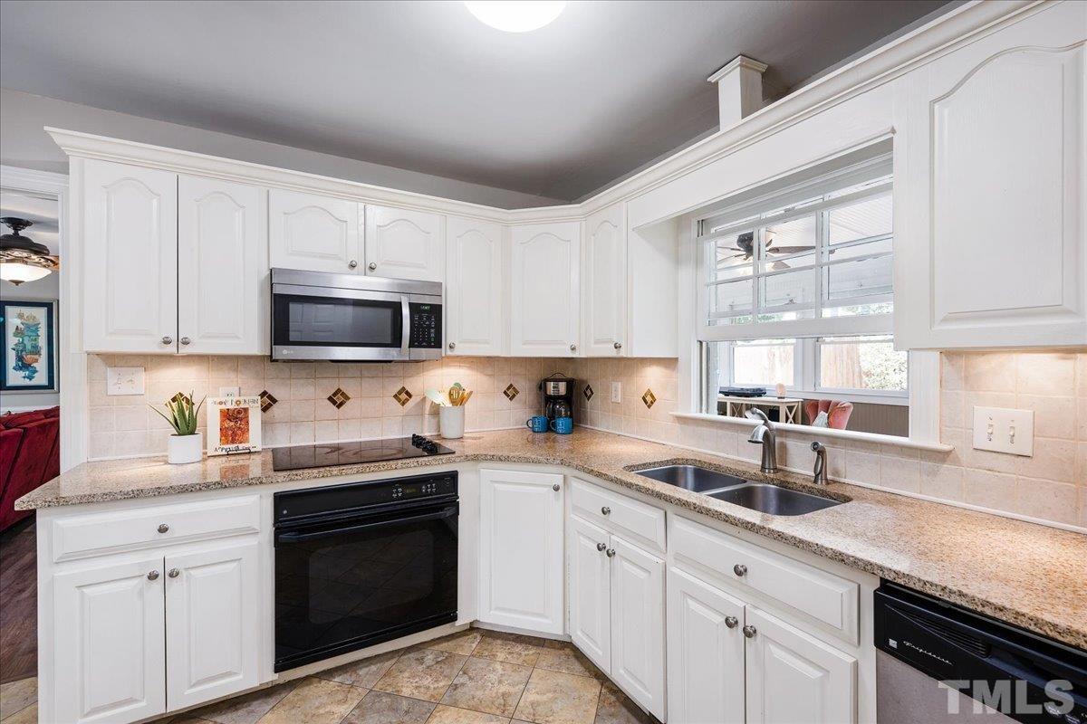 1313 Falls Church Road Raleigh, NC 27609 - Photo 21 of 40 a kitchen with stainless steel appliances granite countertop white cabinets a sink and a stove