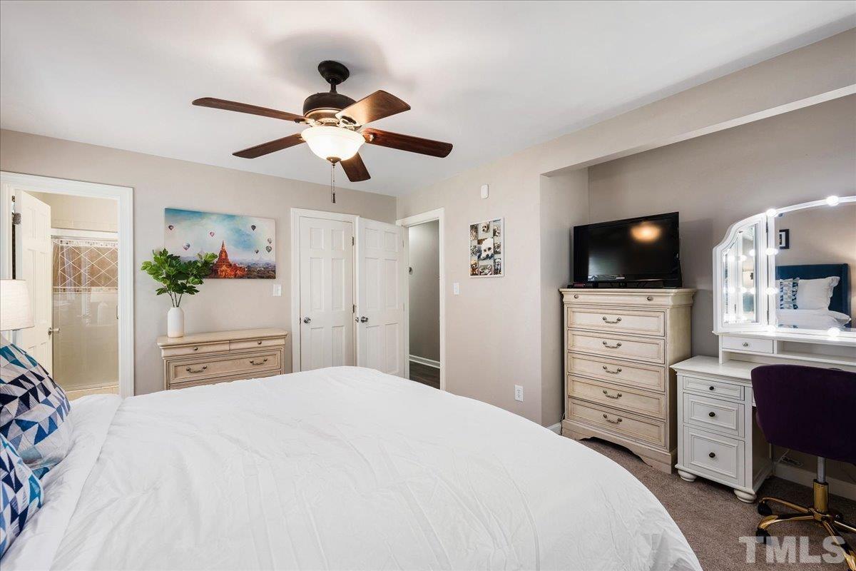 1313 Falls Church Road Raleigh, NC 27609 - Photo 24 of 40 a bedroom with a bed a flat screen tv and a chandelier