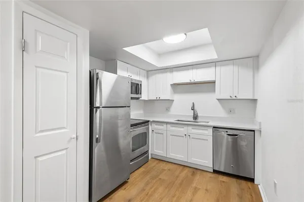 a kitchen with stainless steel appliances granite countertop white refrigerator a sink and white cabinets