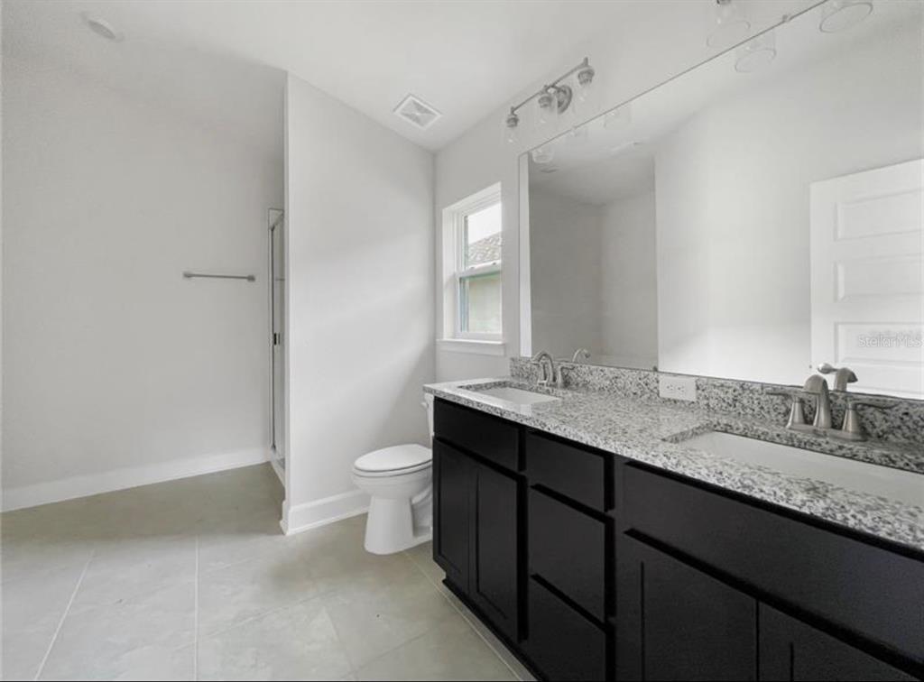 7592 Bent Tree Loop St. Cloud, FL 34773 - Photo 7 of 12 a bathroom with a granite countertop sink a toilet and a mirror