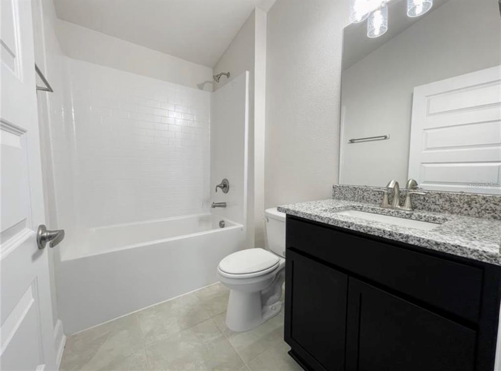 7592 Bent Tree Loop St. Cloud, FL 34773 - Photo 9 of 12 a bathroom with a granite countertop sink a toilet a mirror and bathtub