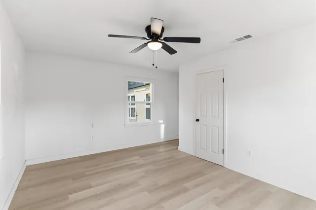 a view of empty room with wooden floor and ceiling fan