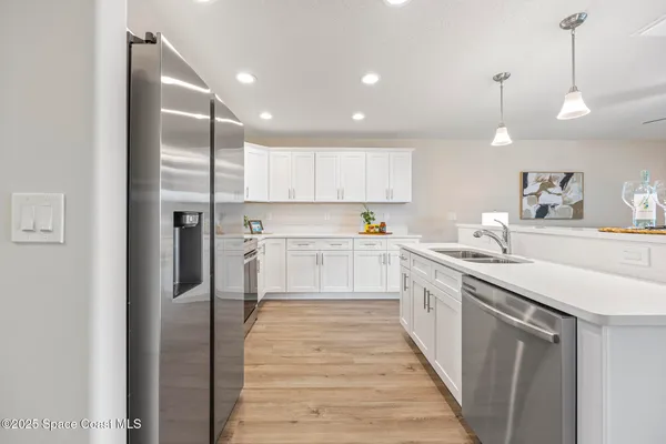 a kitchen with stainless steel appliances granite countertop a refrigerator a sink and white cabinets