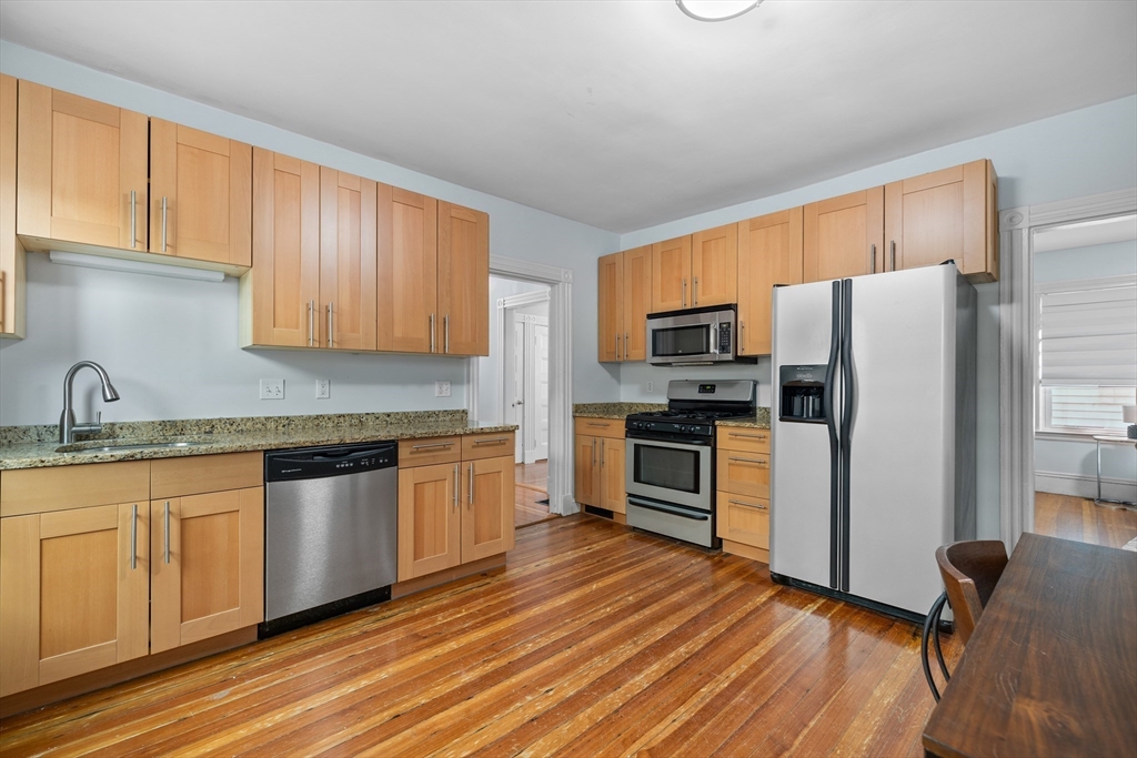 41-43 White Place Brookline, MA 02445 - Photo 5 of 14 a kitchen with granite countertop wooden floors stainless steel appliances and sink
