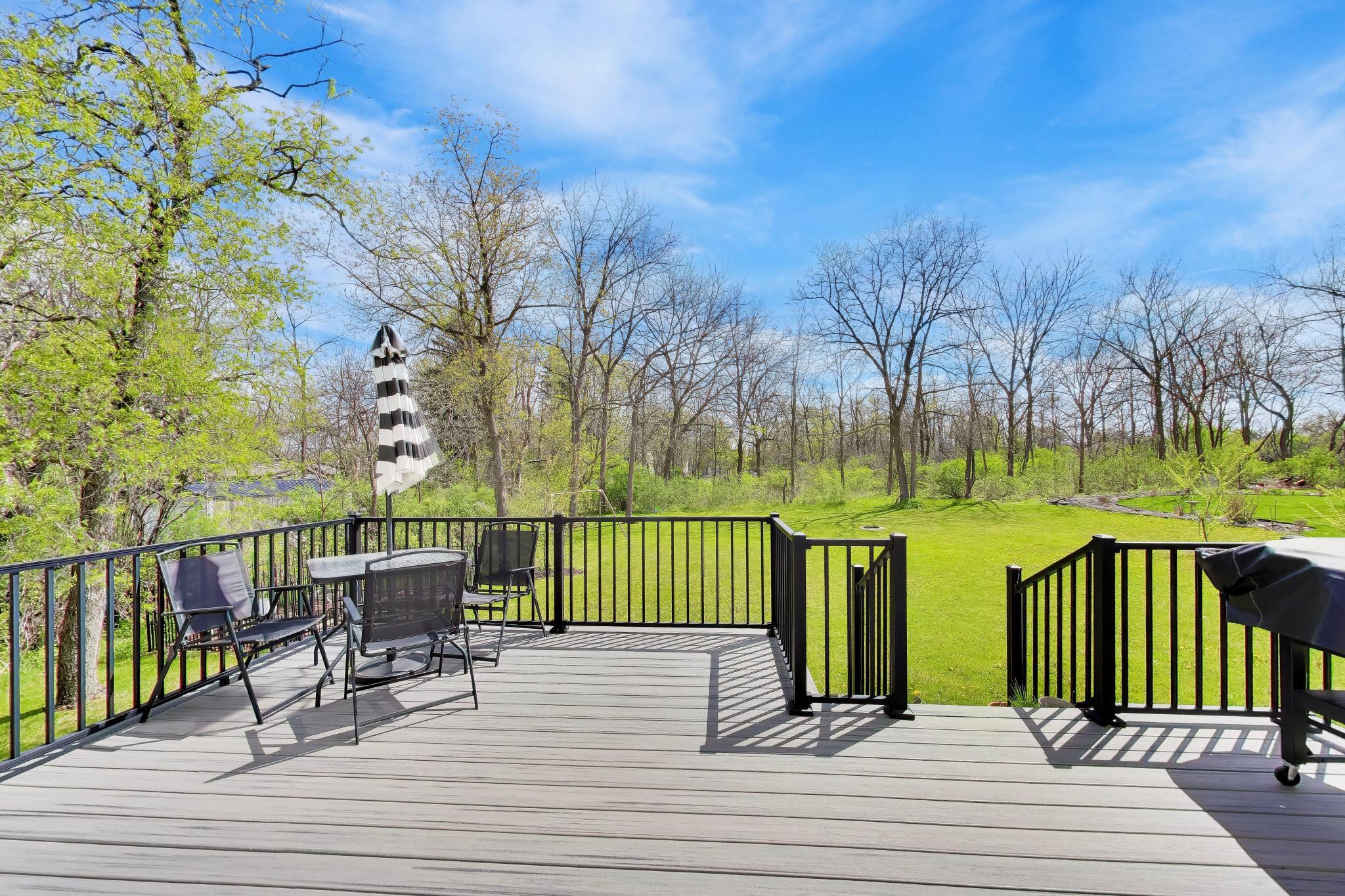 N2392 Mildred Street Delavan, WI 53115 - Photo 7 of 41 High-quality Trex deck overlooking a deep, green backyard with a peaceful wooded backdrop.
