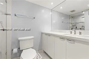 a bathroom with a toilet a sink a mirror and vanity