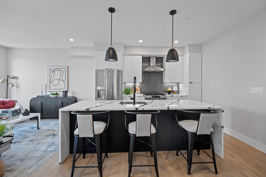 68 Liverpool Street, Unit 3 Boston, MA 02128 - Photo 2 of 6 a kitchen with stainless steel appliances kitchen island a table and chairs in it