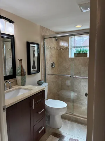 a bathroom with a granite countertop sink toilet a mirror and shower