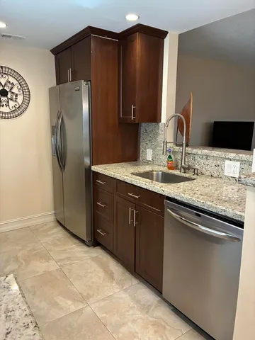 a kitchen with stainless steel appliances granite countertop a refrigerator and a sink