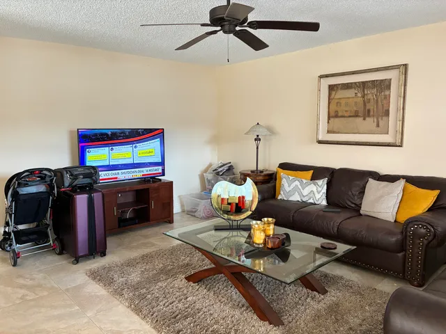 a living room with furniture a flat screen tv and a ceiling fan
