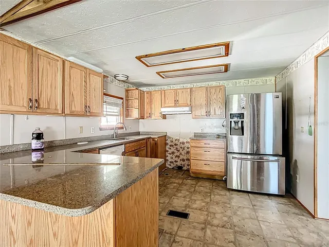 a kitchen with stainless steel appliances granite countertop a refrigerator a stove and a sink