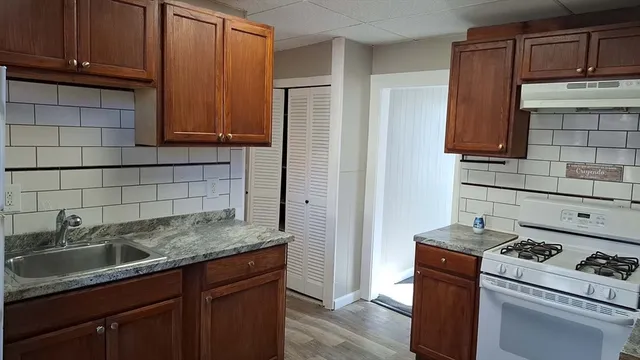 a kitchen with granite countertop a sink stove and cabinets