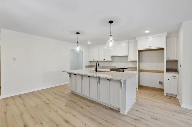 a kitchen with kitchen island a sink stainless steel appliances and white cabinets