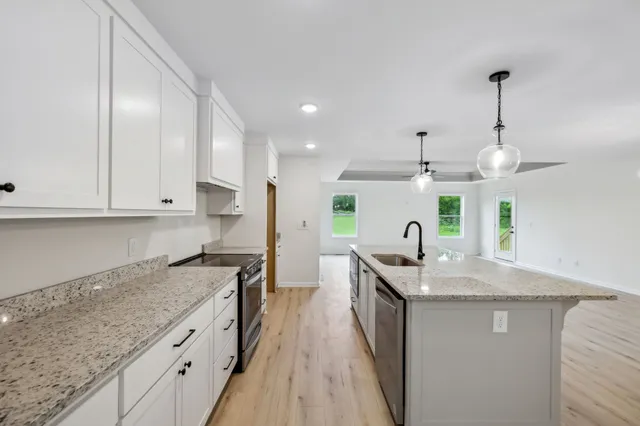 a kitchen with stainless steel appliances granite countertop a sink a stove and a wooden floors