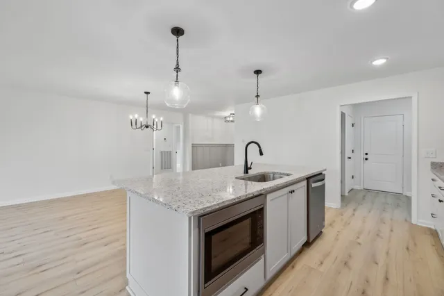 a kitchen with stainless steel appliances granite countertop a sink a stove and a wooden floors