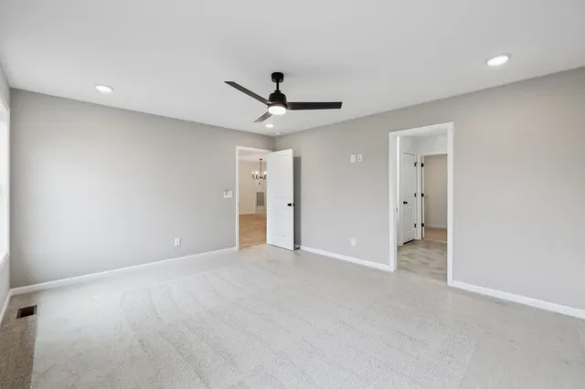 an empty room with a ceiling fan and a window
