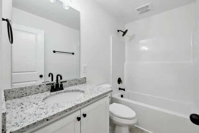 a bathroom with a granite countertop sink a toilet and a bathtub