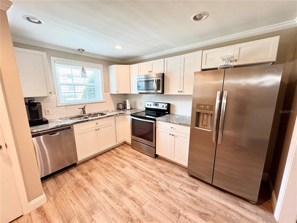 4318 Lake Underhill Road, Unit 17 Orlando, FL 32803 - Photo 11 of 12 a kitchen with white cabinets and stainless steel appliances