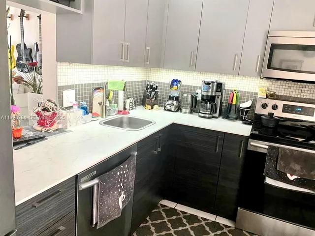 a kitchen with stainless steel appliances a sink stove and microwave