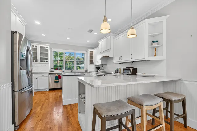 a kitchen with stainless steel appliances granite countertop a refrigerator a sink dishwasher a stove and white cabinets with wooden floor