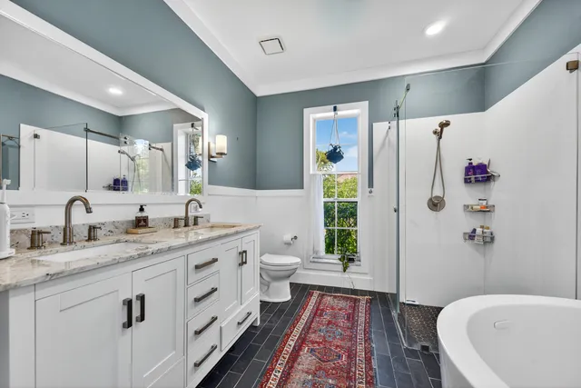 a spacious bathroom with a granite countertop sink toilet a shower a mirror and vanity