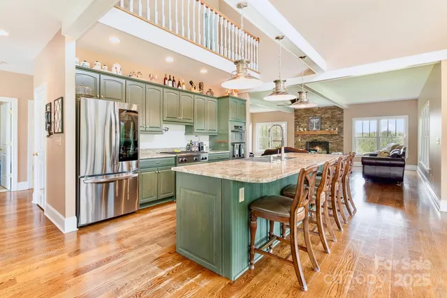 a kitchen with stainless steel appliances kitchen island granite countertop a table chairs and a refrigerator