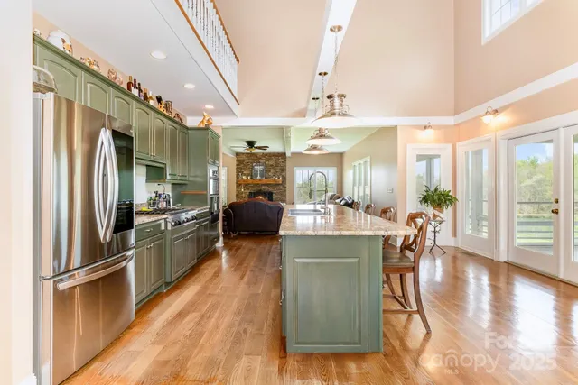a kitchen with stainless steel appliances kitchen island granite countertop a refrigerator a stove and a wooden floors