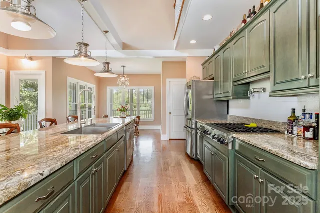 a kitchen with granite countertop a sink a counter top space stainless steel appliances and cabinets