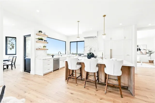 a room with stainless steel appliances kitchen island granite countertop a dining table chairs and view living room