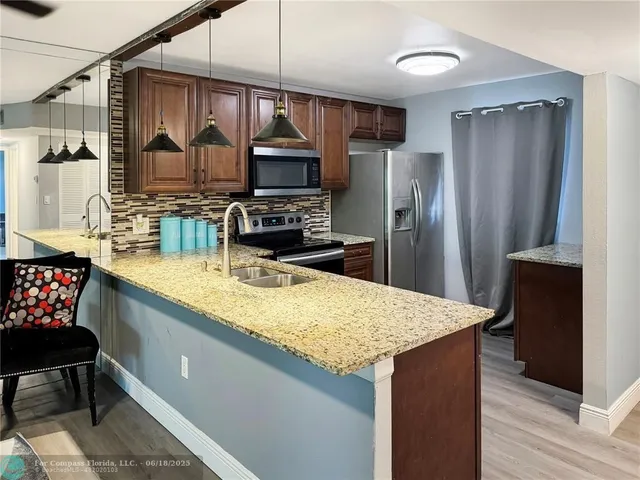 a kitchen with stainless steel appliances granite countertop a sink a stove and refrigerator