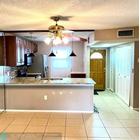 a view of a kitchen with a sink stainless steel appliances granite counter tops and a view of living room
