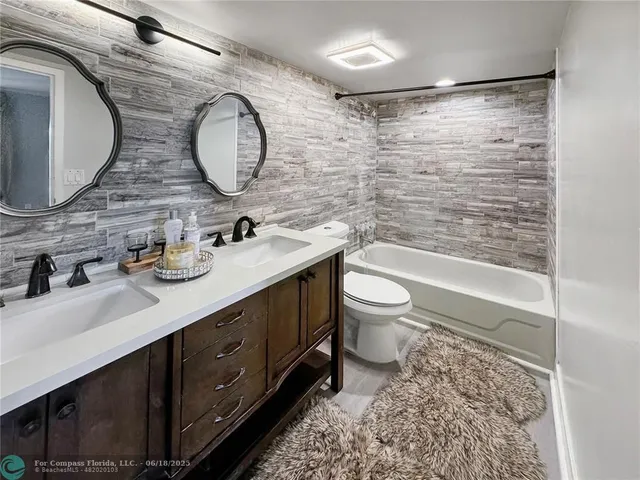 a bathroom with a double vanity sink toilet mirror and shower