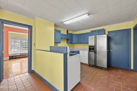 a view of a kitchen with a fridge and wooden floor
