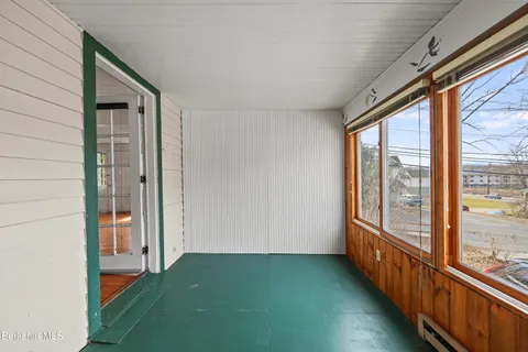 a view of a kitchen in an empty room with a window and wooden floor