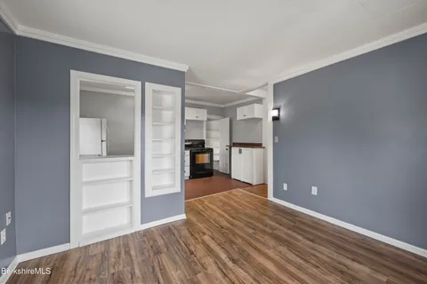 a view of an empty room with window and wooden floor