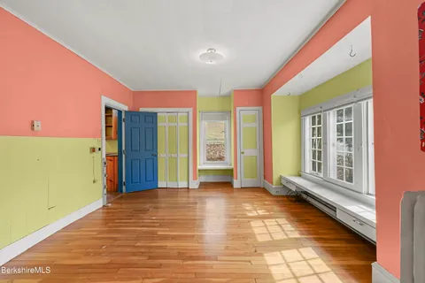 a view of an empty room with window and wooden floor