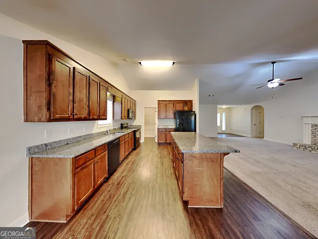 a large kitchen with stainless steel appliances granite countertop plenty wooden cabinets counter space and wooden floor