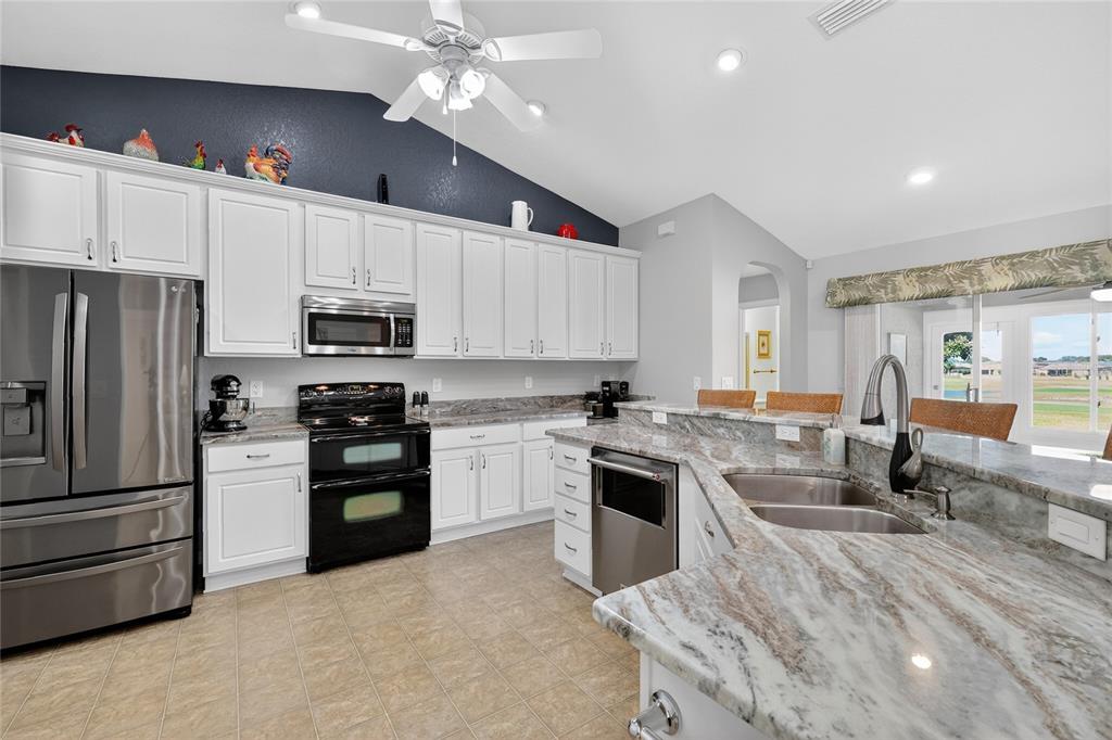 12384 Southeast 176th Loop Summerfield, FL 34491 - Photo 14 of 30 a kitchen with kitchen island granite countertop a stove sink and refrigerator