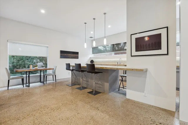 a kitchen with stainless steel appliances granite countertop a stove a refrigerator a kitchen island with chairs and white cabinets