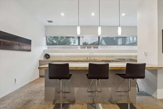 a large kitchen with stainless steel appliances kitchen island a large counter top a sink a stove and a refrigerator