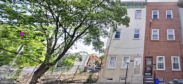 a backyard of a house with wooden fence and large trees