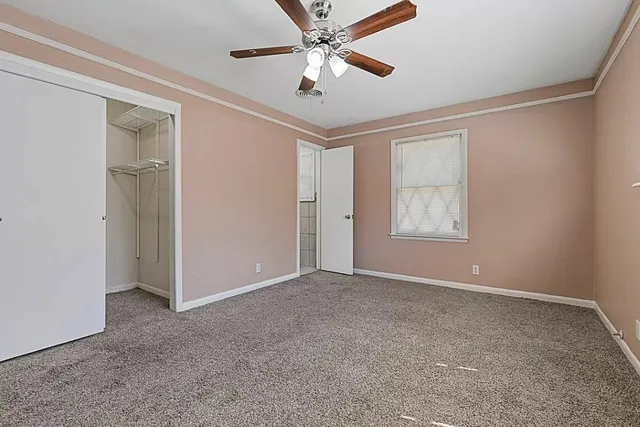 an empty room with windows and fan