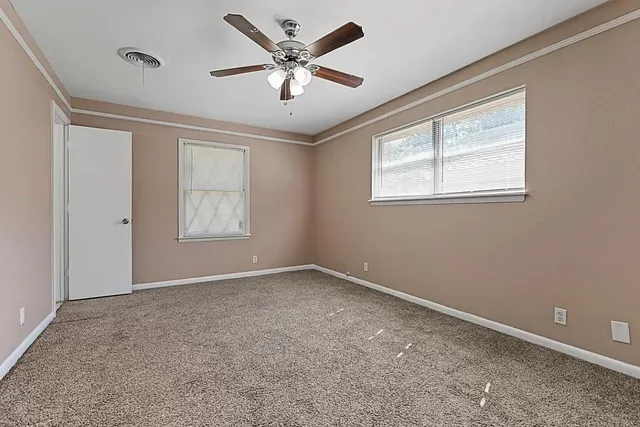 a view of empty room with wooden floor and ceiling fan